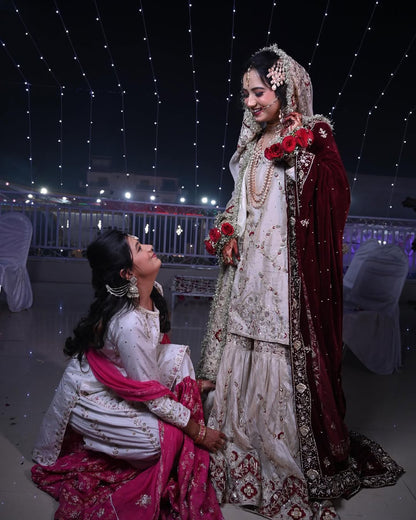 Two women in traditional attire standing under a starry sky with decorative lights.